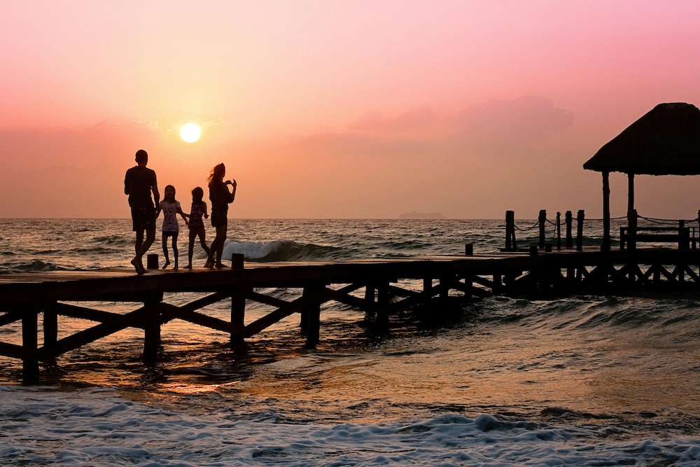 Family walking along pier at sunset